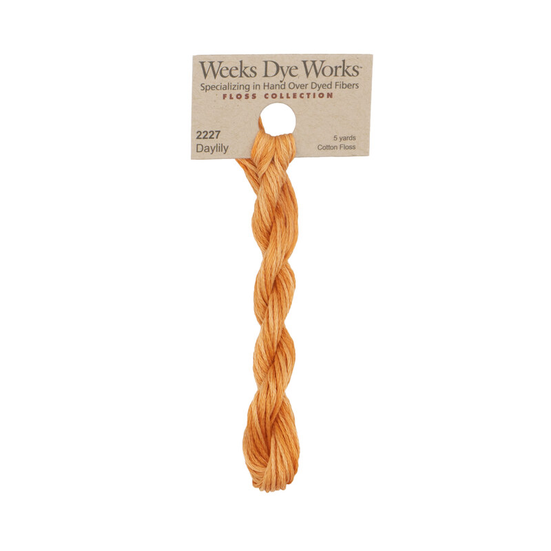 A skein of cantaloupe embroidery floss, twisted and bundled, with a tan label featuring the brand name and color information.