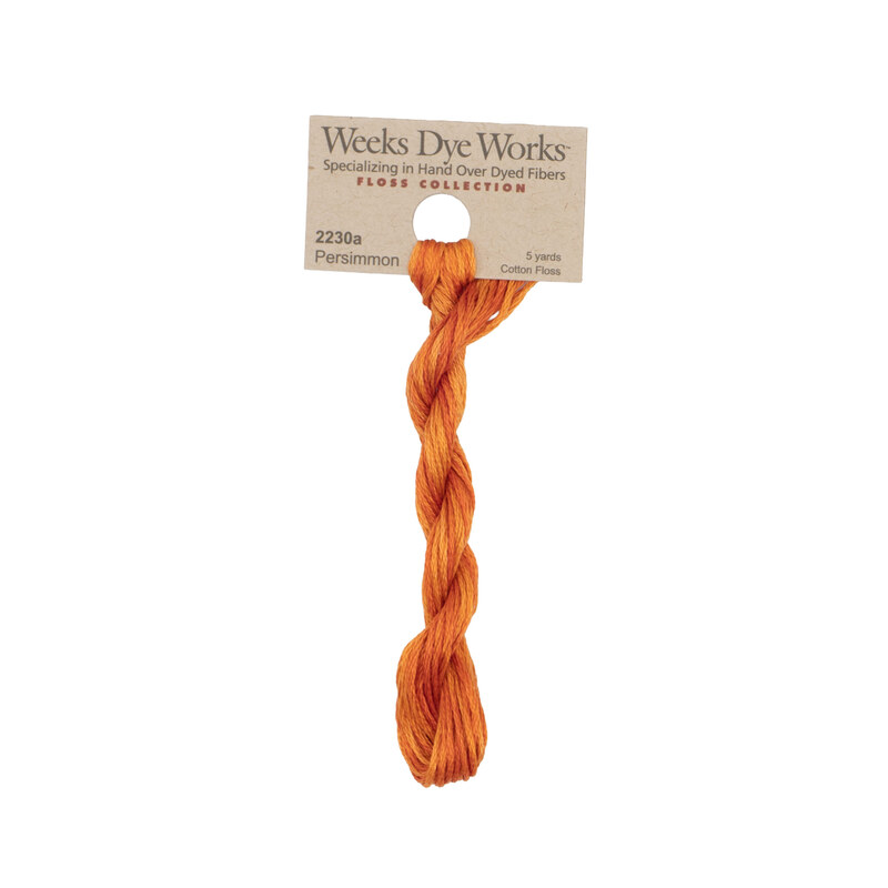 A skein of pumpkin orange embroidery floss, twisted and bundled, with a tan label featuring the brand name and color information.