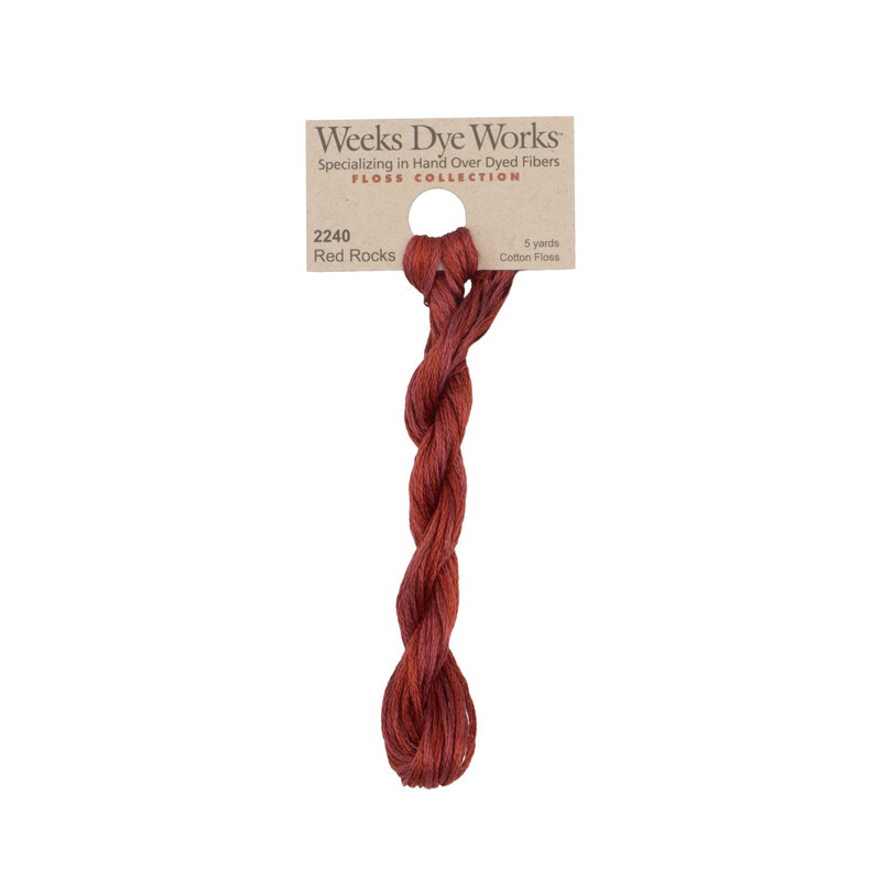 A skein of dark cherry embroidery floss, twisted and bundled, with a tan label featuring the brand name and color information.