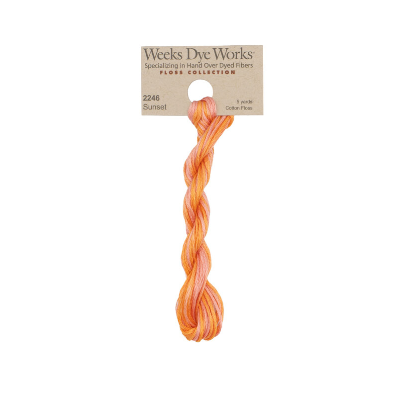 A skein of Variegated Pink and Peach embroidery floss, twisted and bundled, with a tan label featuring the brand name and color information.