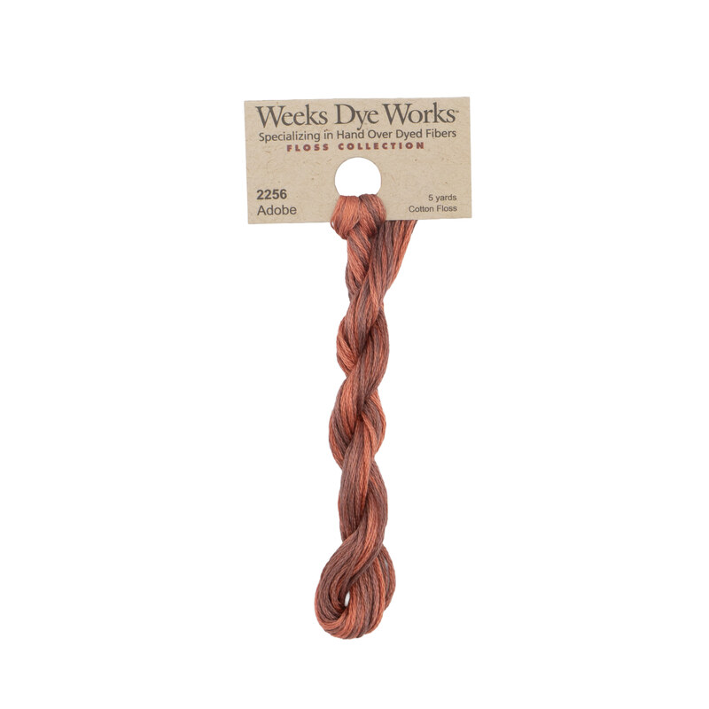 A skein of Variegated Terra Cotta and Earth Brown embroidery floss, twisted and bundled, with a tan label featuring the brand name and color information.