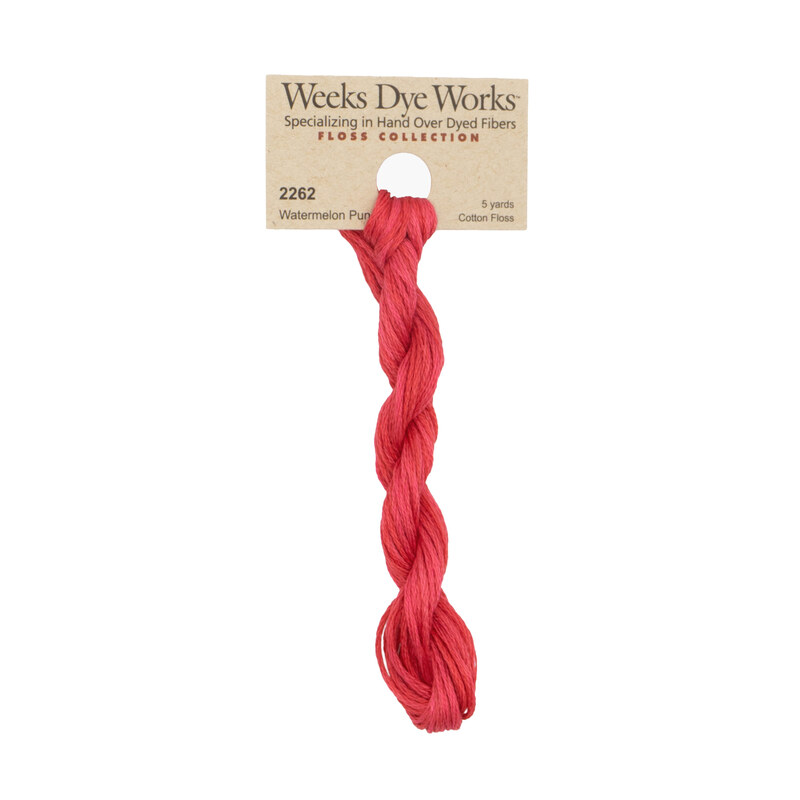 A skein of watermelon red embroidery floss, twisted and bundled, with a tan label featuring the brand name and color information.