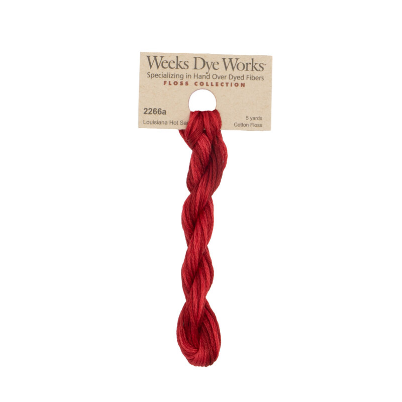 A skein of Cayenne red embroidery floss, twisted and bundled, with a tan label featuring the brand name and color information.