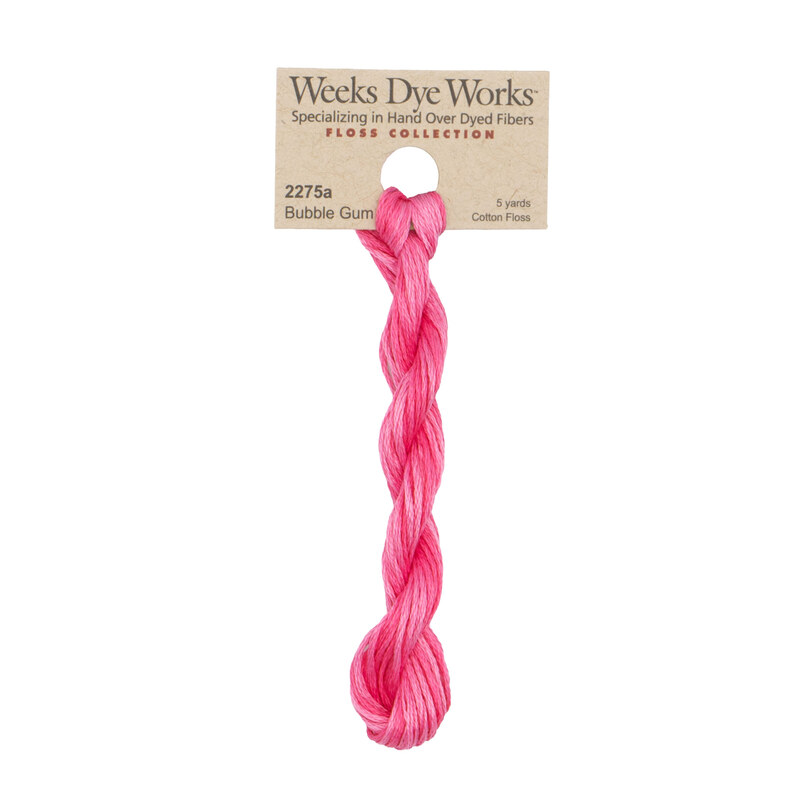 A skein of bright pink embroidery floss, twisted and bundled, with a tan label featuring the brand name and color information.