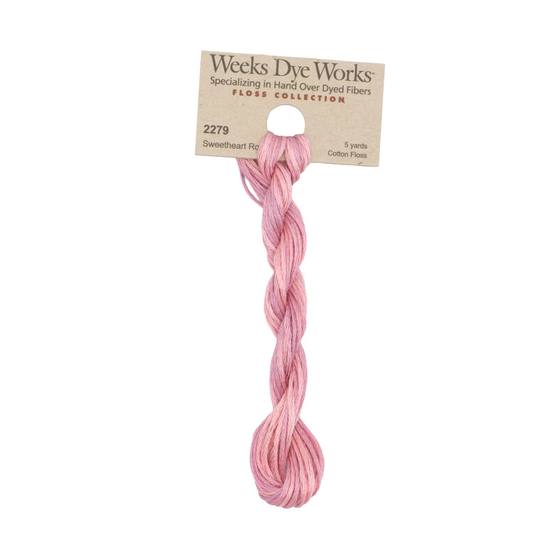 A skein of blush pink embroidery floss, twisted and bundled, with a tan label featuring the brand name and color information.