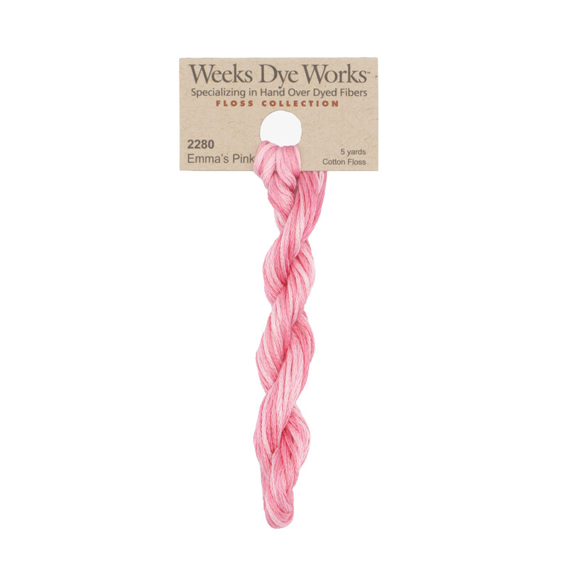 A skein of variegated pink embroidery floss, twisted and bundled, with a tan label featuring the brand name and color information.
