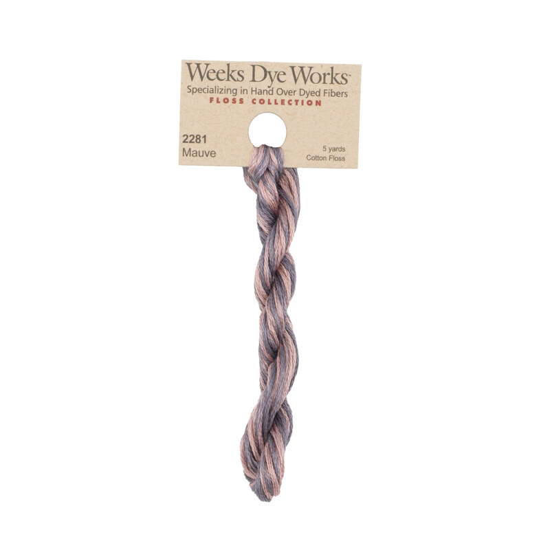 A skein of dusty pink and lilac embroidery floss, twisted and bundled, with a tan label featuring the brand name and color information.