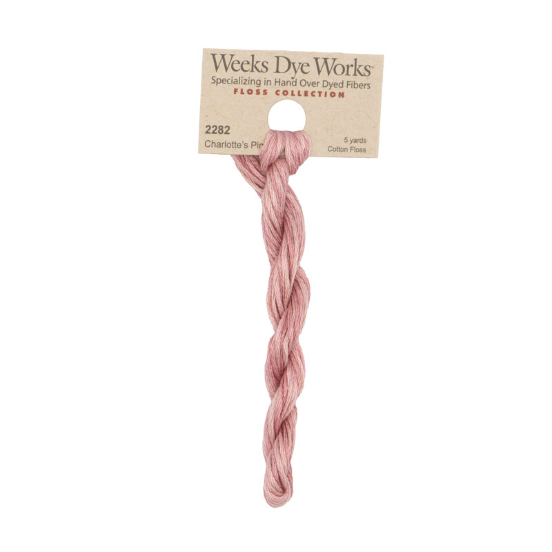 A skein of ballerina pink embroidery floss, twisted and bundled, with a tan label featuring the brand name and color information.