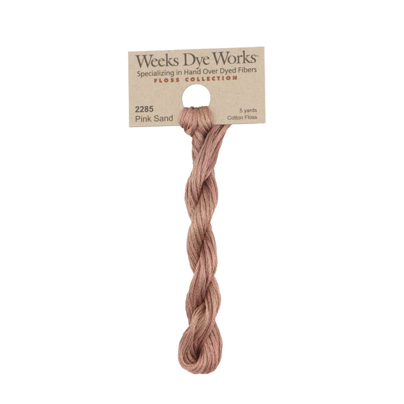 A skein of rosy taupe embroidery floss, twisted and bundled, with a tan label featuring the brand name and color information.
