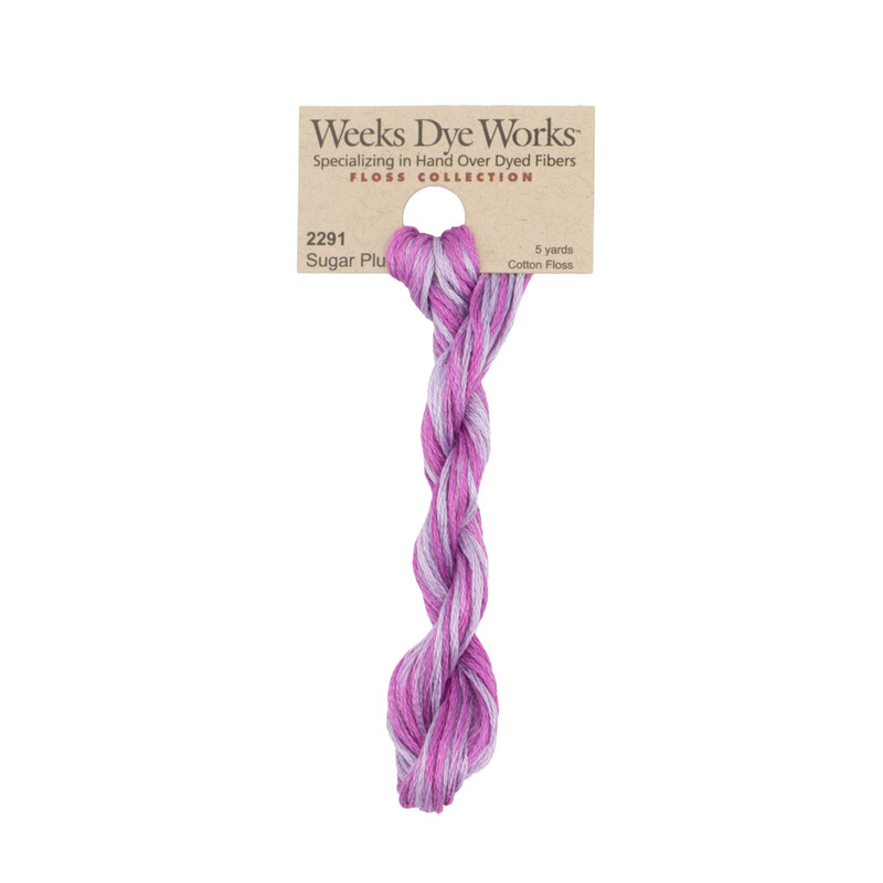 A skein of variegated magenta and purple embroidery floss, twisted and bundled, with a tan label featuring the brand name and color information.