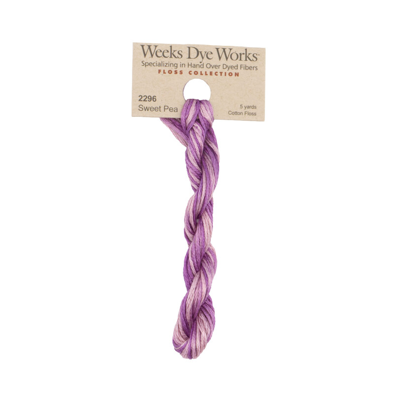A skein of light pink and purple embroidery floss, twisted and bundled, with a tan label featuring the brand name and color information.
