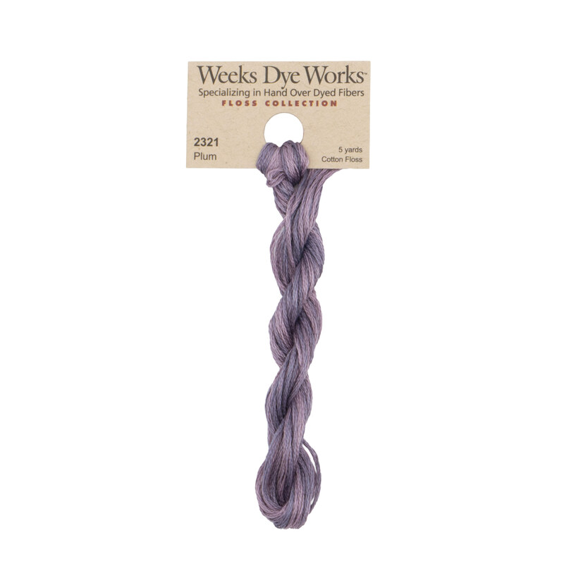 A skein of muted violet embroidery floss, twisted and bundled, with a tan label featuring the brand name and color information.