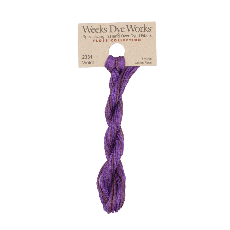 A skein of eggplant purple embroidery floss, twisted and bundled, with a tan label featuring the brand name and color information.
