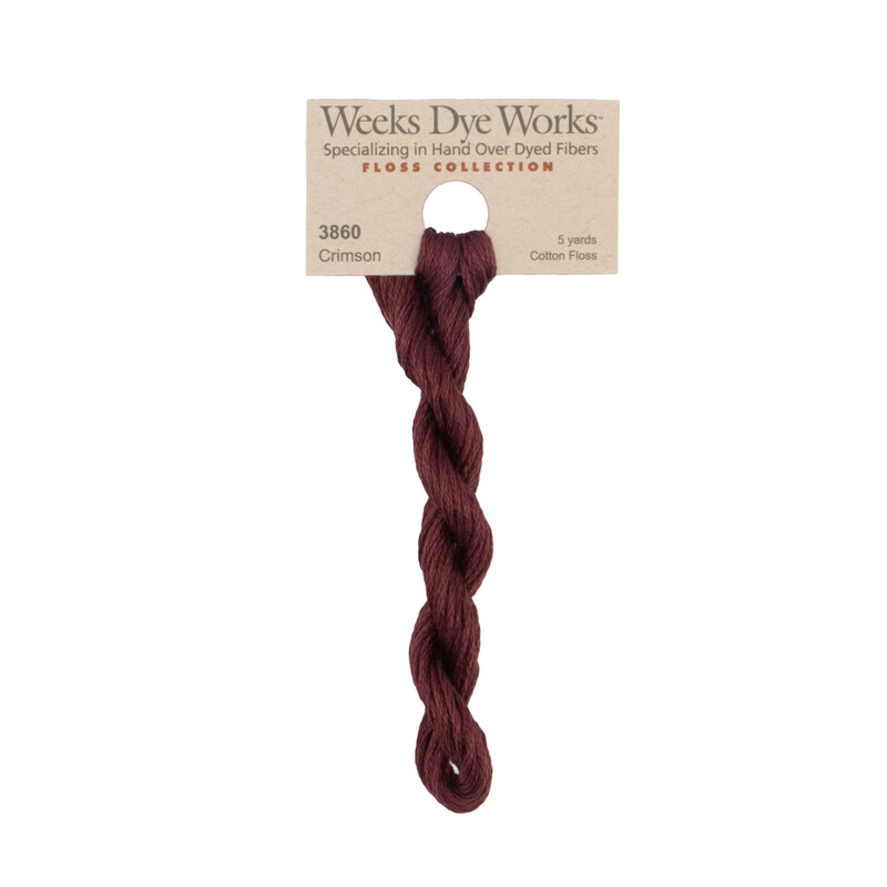 A skein of oxblood embroidery floss, twisted and bundled, with a tan label featuring the brand name and color information.