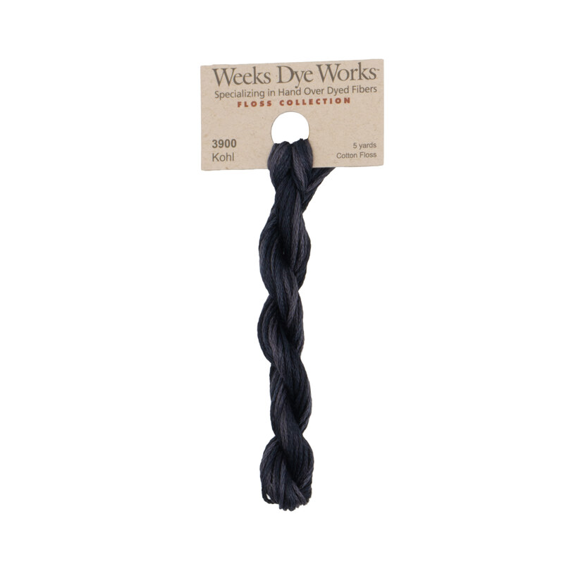 A skein of soft black embroidery floss, twisted and bundled, with a tan label featuring the brand name and color information.