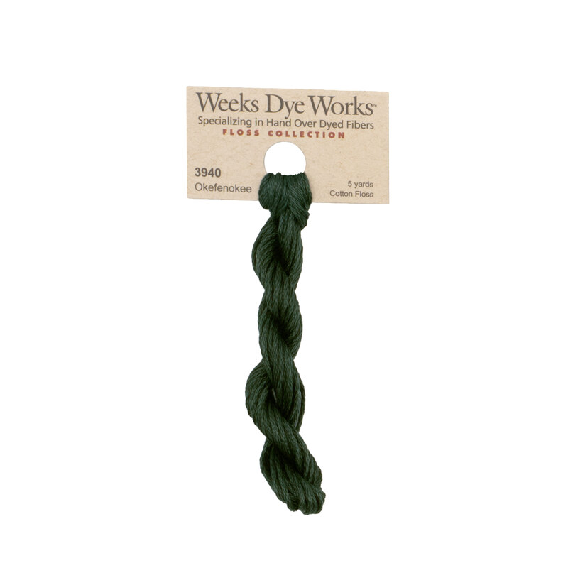 A skein of hunter green embroidery floss, twisted and bundled, with a tan label featuring the brand name and color information.?