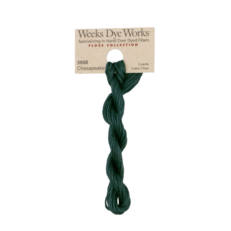 A skein of dark teal embroidery floss, twisted and bundled, with a tan label featuring the brand name and color information.