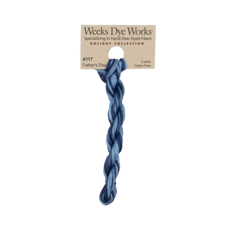 A skein of dark and denim blue embroidery floss, twisted and bundled, with a tan label featuring the brand name and color information.