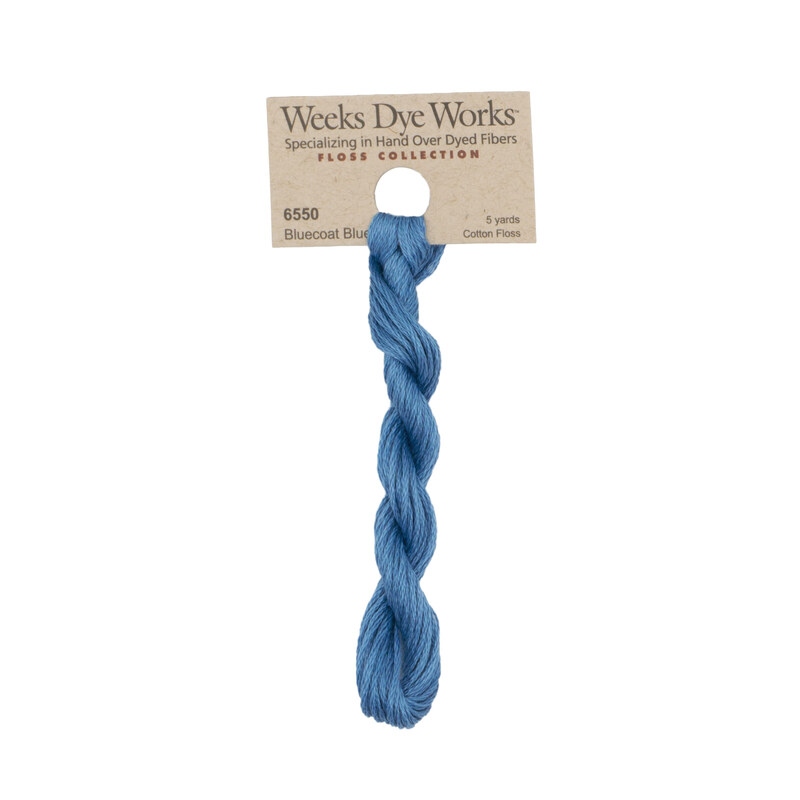 A skein of sky blue embroidery floss, twisted and bundled, with a tan label featuring the brand name and color information.