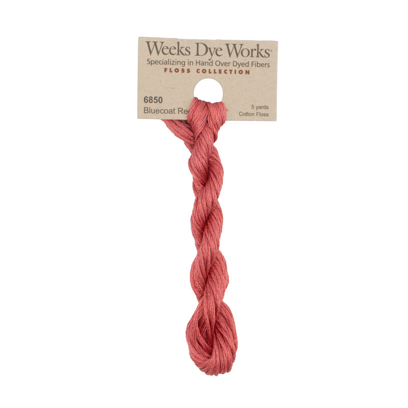 A skein of salmon pink embroidery floss, twisted and bundled, with a tan label featuring the brand name and color information.
