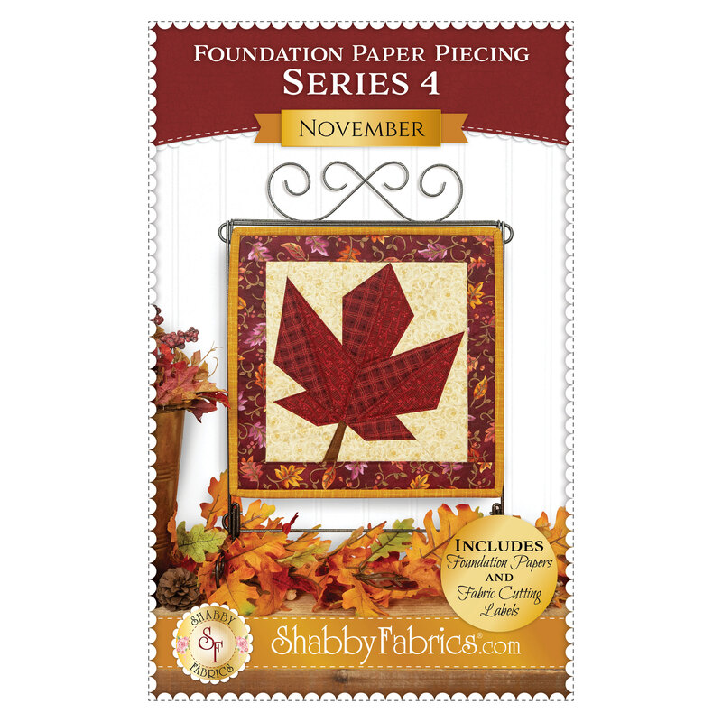 Front cover of the pattern showing the completed Foundation Paper Piecing Series 4 November project, a maple leaf in warm rust red, mahogany, and cream prints, displayed on a craft hanger and staged with coordinating foliage.