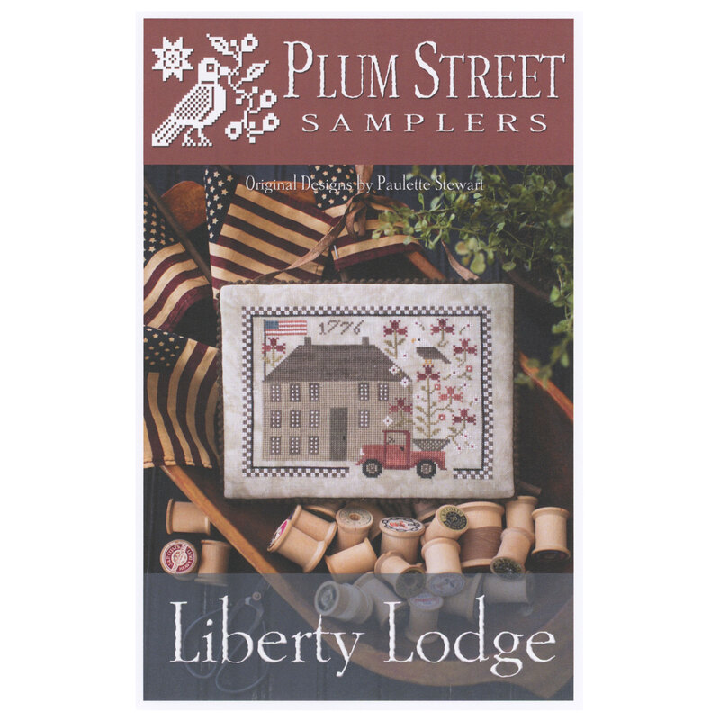 Front of pattern showing the completed cross stitch design displayed in a bowl filled with wooden spools and American flags.