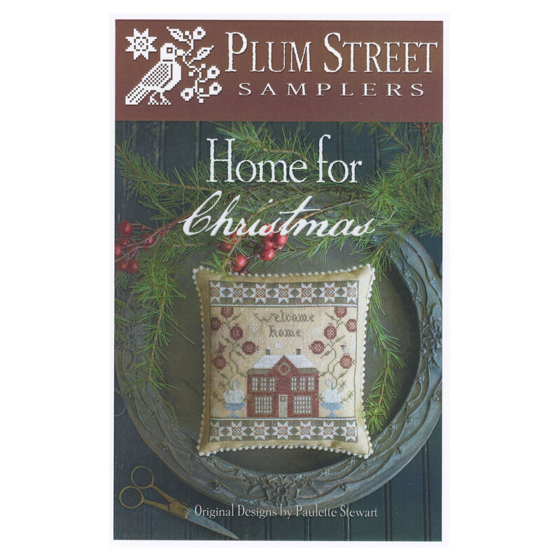 Front of pattern showing the completed cross stitch design finished as a pillow on a decorative plate with greenery.