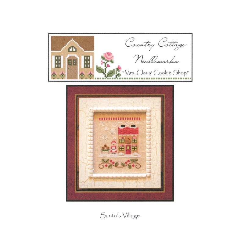 The front image of "Mrs. Claus' Cookie Shop" cross stitch pattern featuring Mrs. Claus next to her cookie shop.