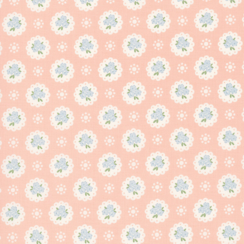 Light peach fabric with a pattern of white doilies containing light blue flowers and white dots
