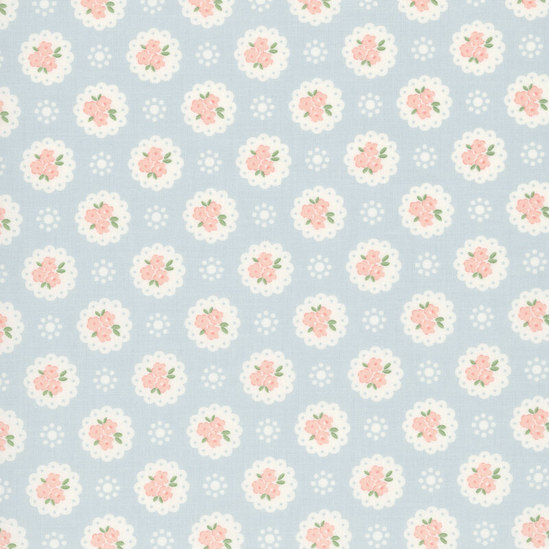 Baby blue fabric with a pattern of white doilies containing light peach flowers and white dots