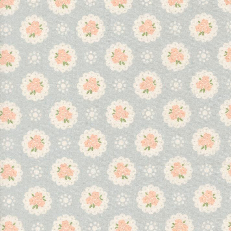 Baby blue fabric with a pattern of white doilies containing light peach flowers and white dots