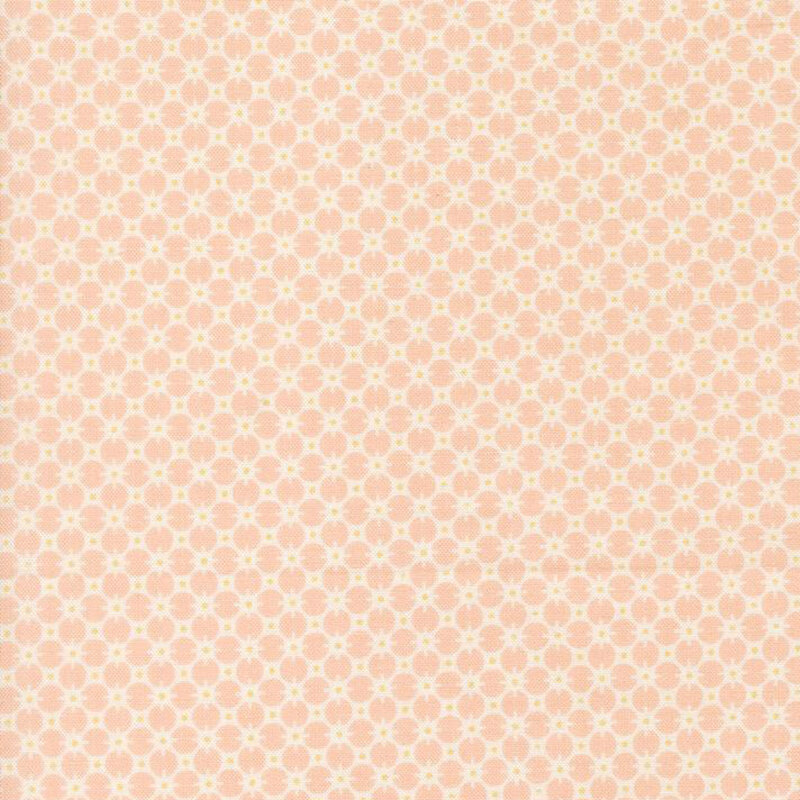 Pastel pink fabric with a cream pattern of circles and yellow dots