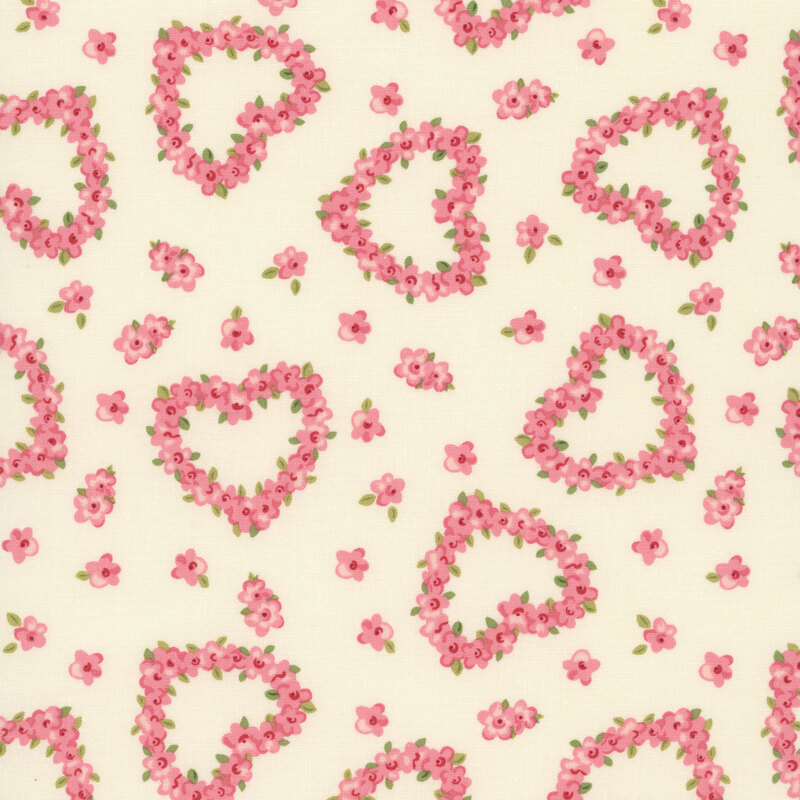 Pink roses in the shape of hearts tossed on a beige fabric with interspersed pink flowers