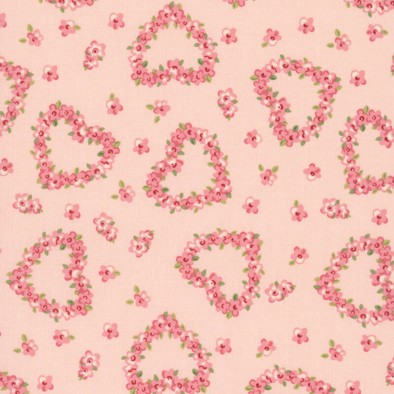 Pink roses in the shape of hearts tossed on blush pink fabric with interspersed pink flowers