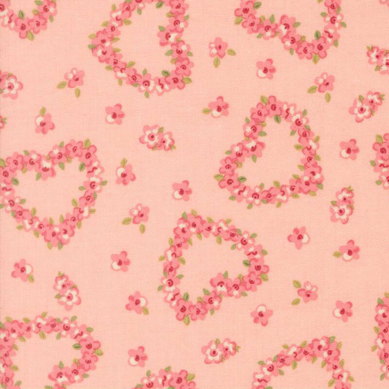 Pink roses in the shape of hearts tossed on blush pink fabric with interspersed pink flowers