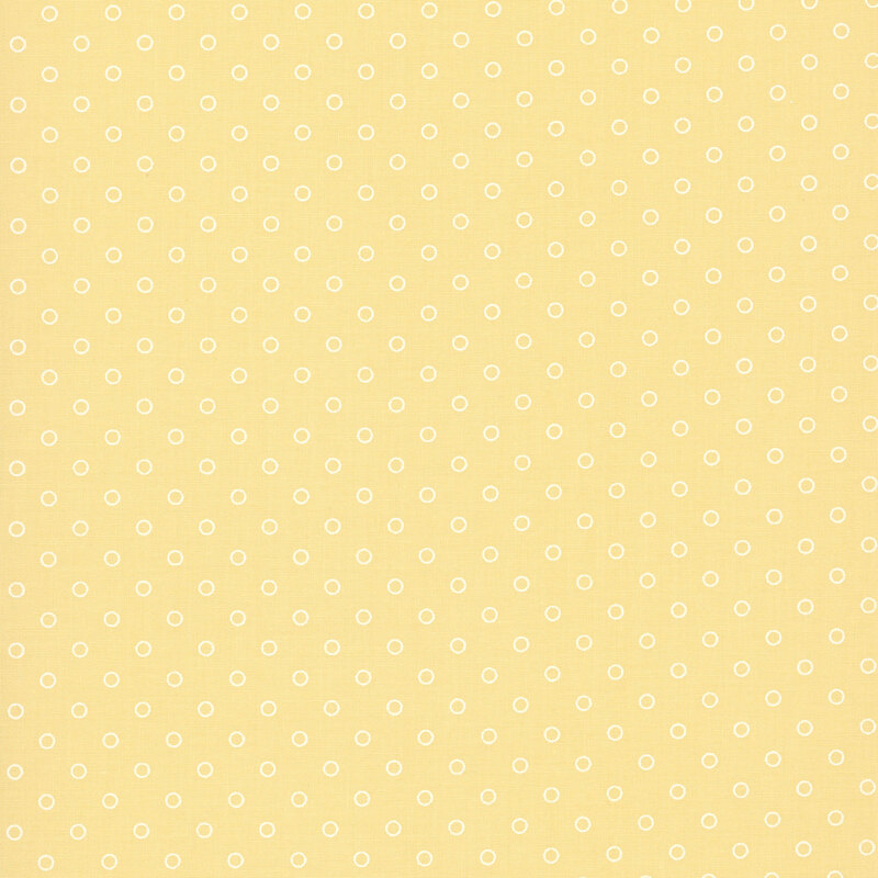 A butter yellow fabric with polka dots in a half drop pattern. 