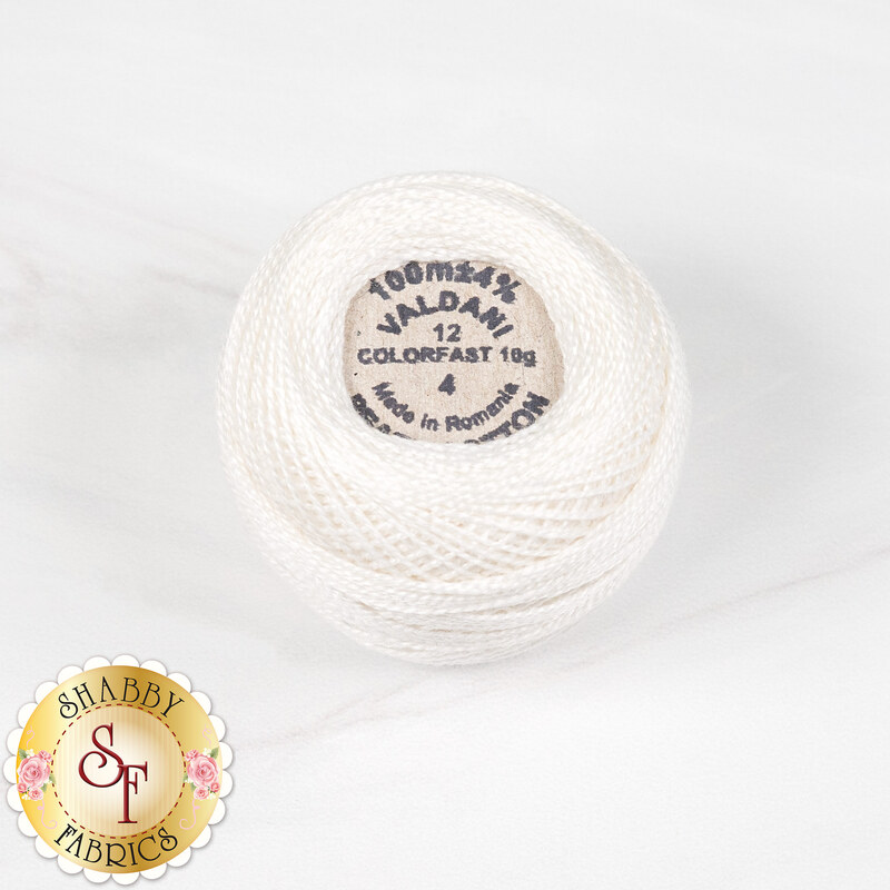 A ball of Valdani Pearl Cotton thread in ivory, isolated on a marbled white background.
