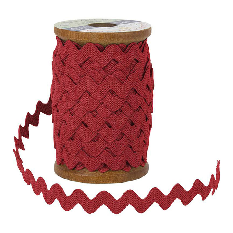 A wooden spool with red ric-rac trim on a white background