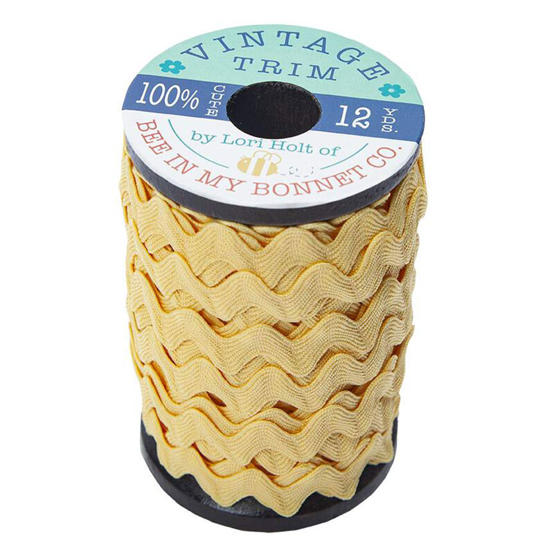 A wooden spool with large sunshine yellow ric-rac trim on a white background