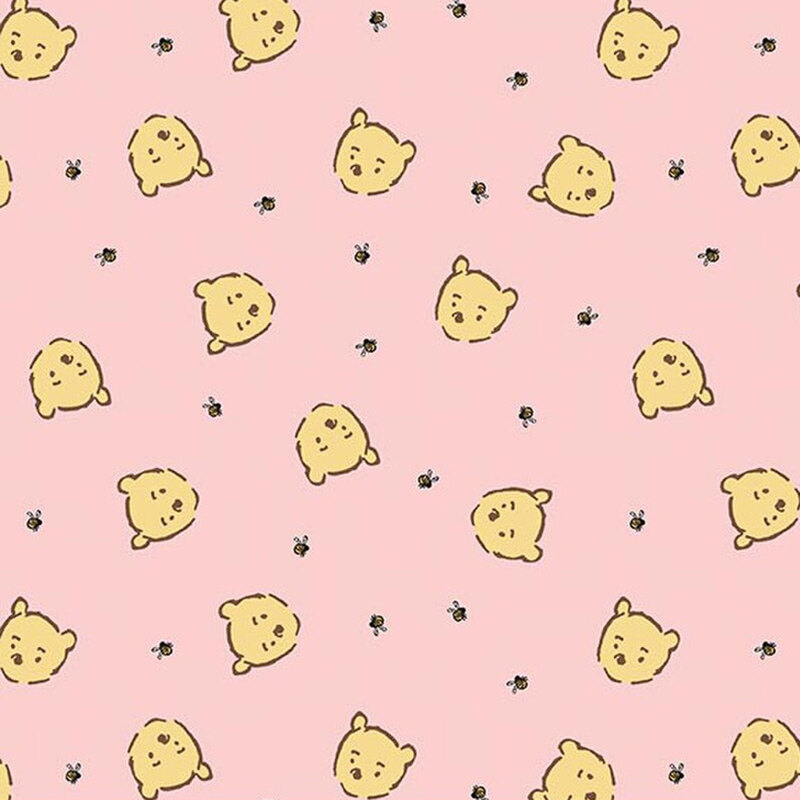 Soft pink fabric with a playful pattern of cartoon Winnie the Pooh faces and small bumblebees.