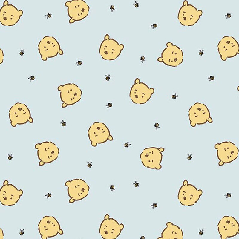 Soft blue fabric with a pattern of cartoon Winnie the Pooh faces and small bumblebees.