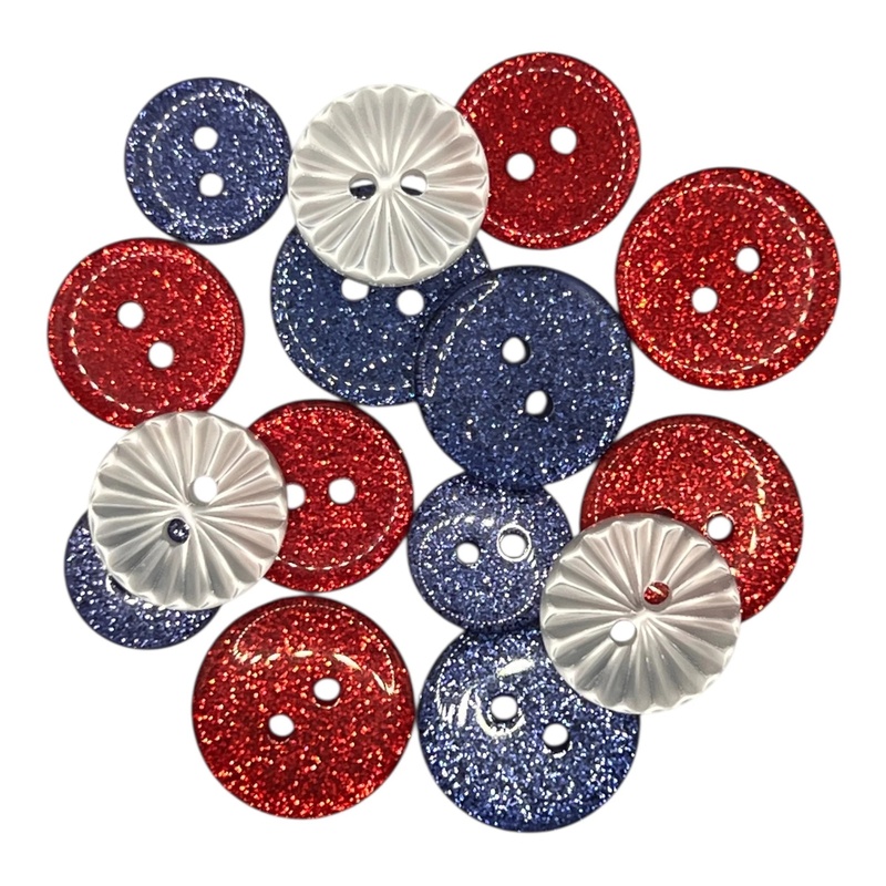 A pile of glittery patriotic themed buttons and embellishments in red, white, and blue.