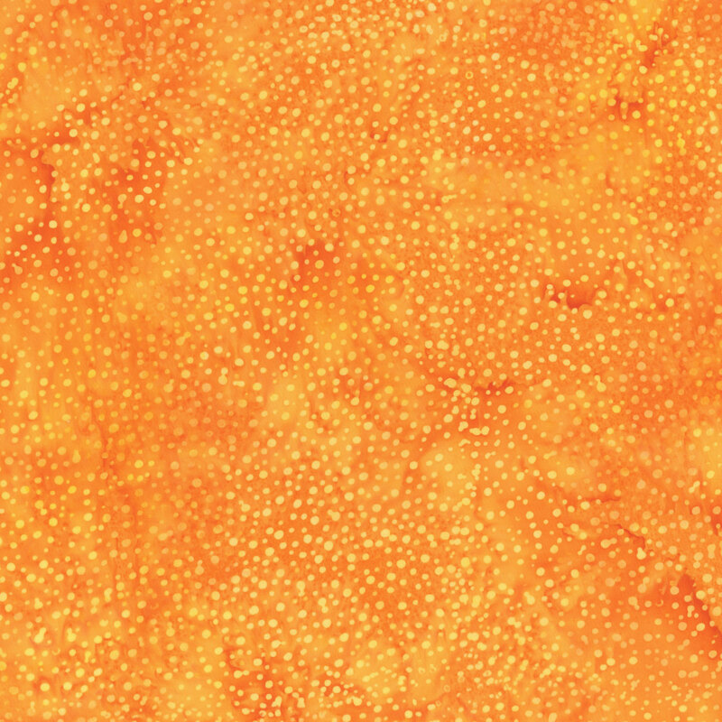 A mottled bright marigold yellow batik fabric with scattered tonal dots.