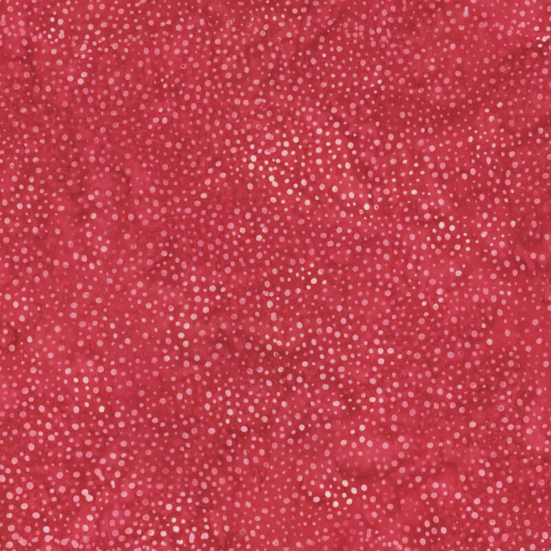 A mottled bright garnet red batik fabric with scattered pink dots.