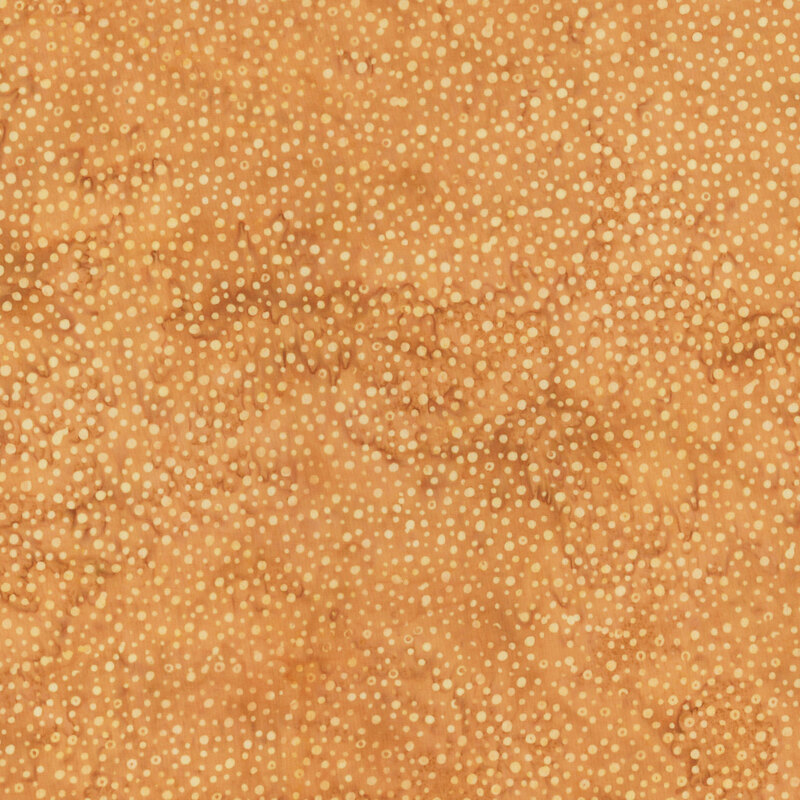 A mottled tan batik fabric with scattered tonal dots.