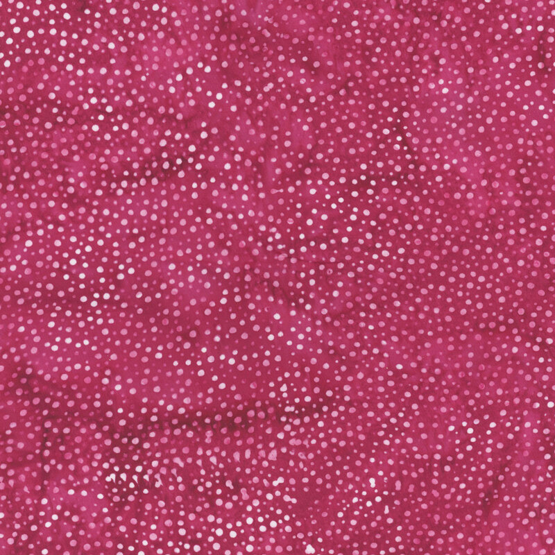 A mottled bright fuchsia batik fabric with scattered light pink dots.