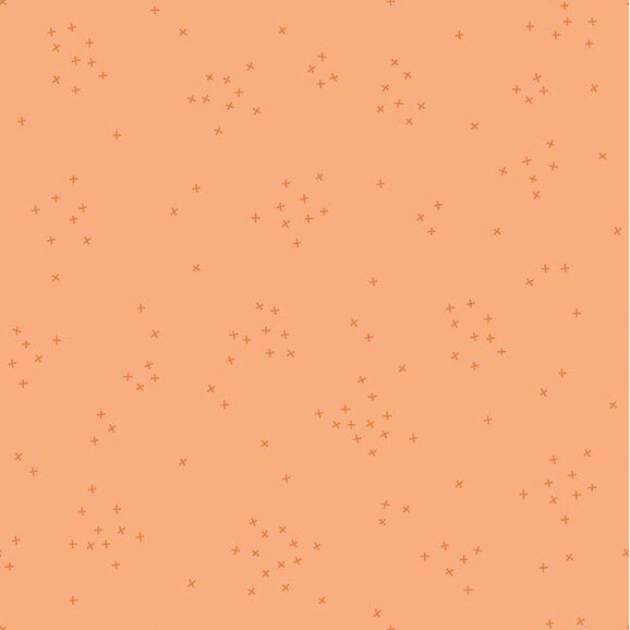 This peach fabric is scattered with tiny tonal crosses clustered together.