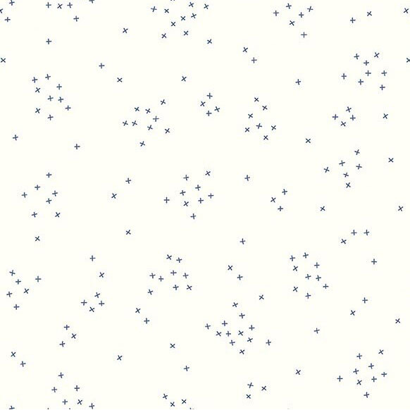 This white fabric is scattered with tiny blue crosses clustered together.