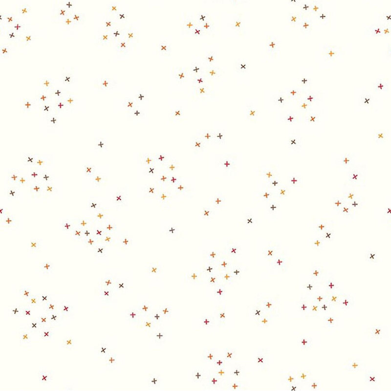 This white fabric is scattered with tiny red, orange, and brown crosses clustered together.