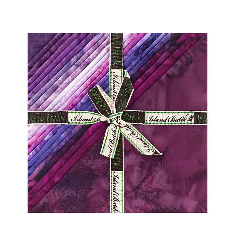 Layered stack of purple mottled fabrics with the left corners folded, tied in an “Island Batik” ribbon.